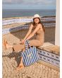 Modelo sentada al sol con la bolsa Roxy Fairy Beach Azul a rayas