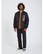Hombre con chaqueta acolchada reversible Volcom Lookster anverso negra posando
