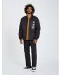 Hombre con chaqueta acolchada reversible Volcom Lookster anverso negra posando