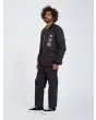 Hombre con chaqueta acolchada reversible Volcom Lookster anverso negra posando lateral