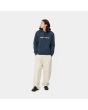 Hombre con sudadera de capucha Carhartt WIP Hooded Carhartt Sweat azul marino con logo blanco frontal 