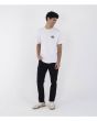 Hombre con camiseta Hurley Floatin blanca combinada con pantalón negro y zapatillas retro estilo skate