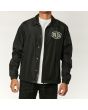 Hombre con chaqueta Deus Ex Machina Venice Coach negra abierta