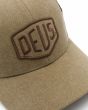 Detalle bordado del logo Deus en marrón de la gorra Deus Shield Trucker  Dijon 