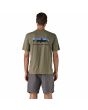 Hombre con camiseta Patagonia Home Water Trout Organic color verde River Rock Green, con gráfico de trucha y mensaje "protect our home water